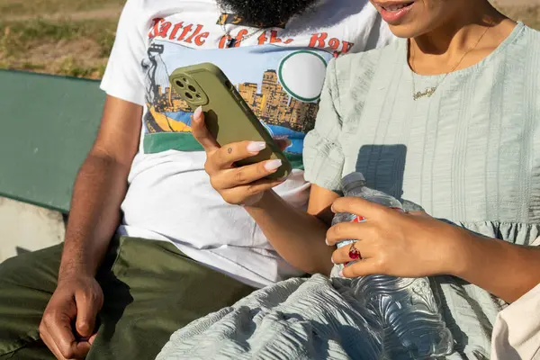 Çift bankta oturuyor ve akıllı telefon kullanıyor.