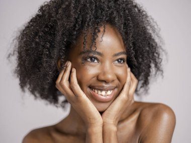 Kıvırcık saçlı, gülümseyen kadının stüdyo portresi.