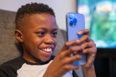 Akıllı telefonlu çocuk kanepede oturuyor.