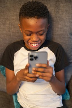 Akıllı telefonlu çocuk kanepede oturuyor.