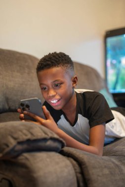 Boy with smart phone lying on sofa