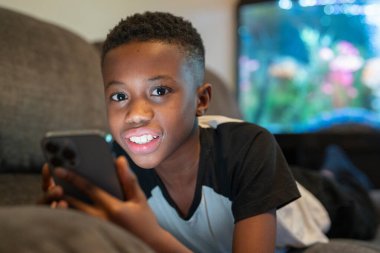Boy with smart phone lying on sofa