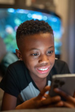 Akıllı telefonlu çocuk kanepede oturuyor.