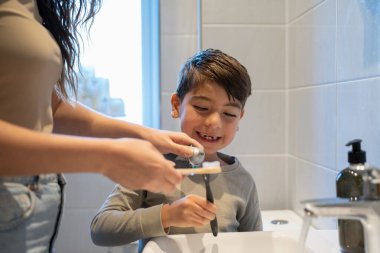 Mother and son (6-7) brushing teeth together
