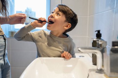 Mother and son (6-7) brushing teeth together