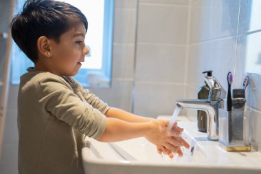 Boy (6-7) washing hands in bathroom