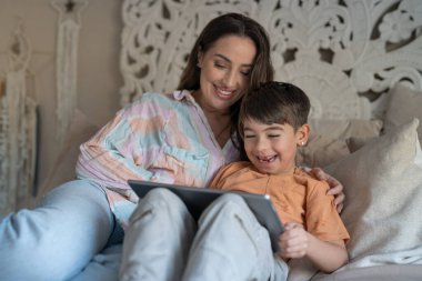 Mother and son (6-7) using digital tablet in bedroom