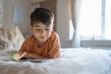Boy (6-7) using digital tablet in bedroom
