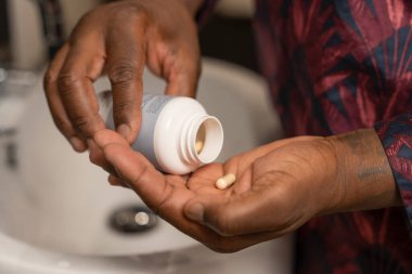 Man taking pills while standing next to bathroom sink