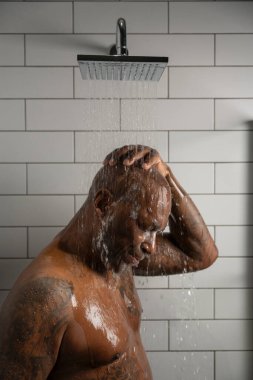 Beyaz duvar arkasında duş alan bir adam. 