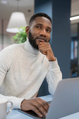 Ofiste dizüstü bilgisayarda çalışan genç adam.