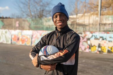 Dışarıda top oynarken gülümseyen futbolcunun portresi.