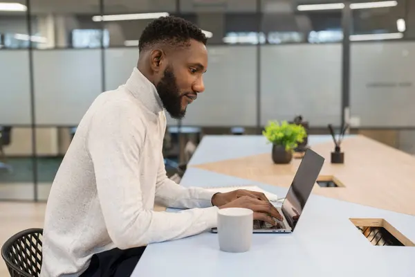 Ofiste dizüstü bilgisayarda çalışan genç adam.