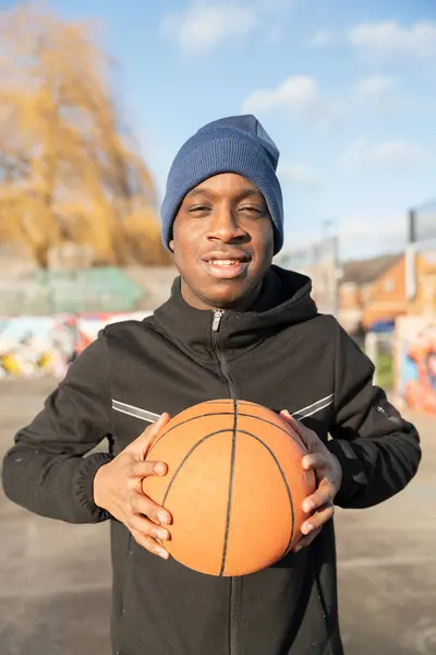 Dışarıda basketbol topuyla gülümseyen bir adamın portresi.