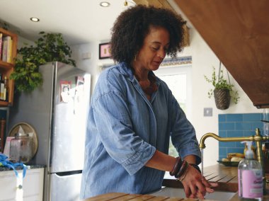Kadın mutfakta ellerini yıkıyor.