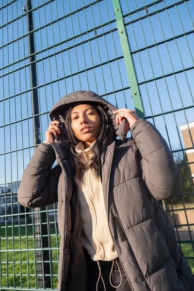 Kapüşonlu ve çitte duran kadın portresi.