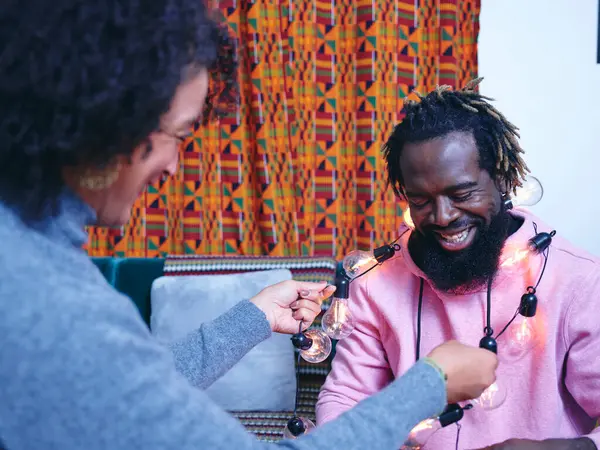 Süslü ampulleri erkeğin boynuna saran kadın.