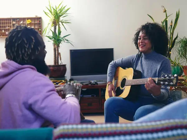 Çift evde akustik gitar çalıyor.
