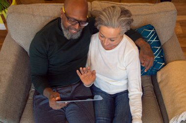 Evde dijital tablet kullanan yaşlı çift