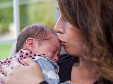 Küçük oğlunu öpen bir kadının yakın çekimi.