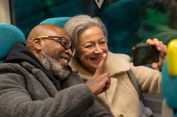 Yaşlı çift trende selfie çekiyor.