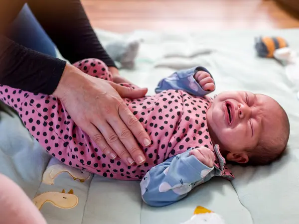 Anne küçük kızın karnını okşuyor.