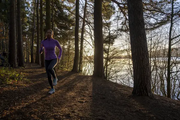 Genç bir kadın ormanda koşuyor.