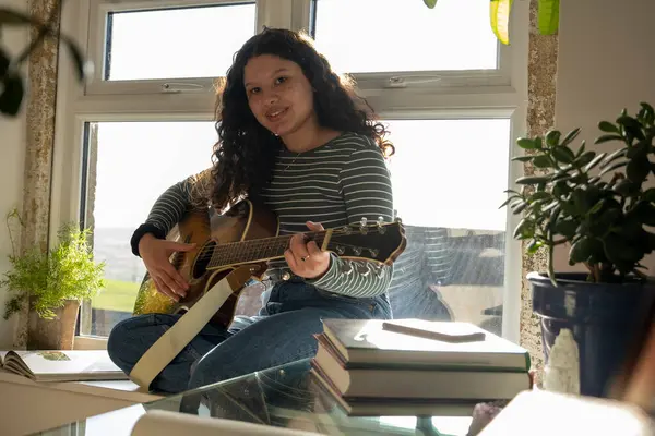 Evde gitar çalan genç bir kadının portresi