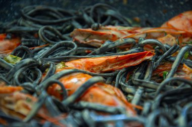 Tereyağlı taze deniz mahsullü siyah spagetti, beyaz şarap ve sarımsak sosu. Taze kaplan karidesli lüks bir tabak..