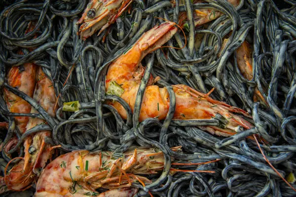 Parmesanlı kremalı sarımsaklı karides. Taze kremalı karides, siyah linguini tarifi. Uluslararası mutfak, lezzetli. İtalyan sosu. Sanatsal gıda konsepti.