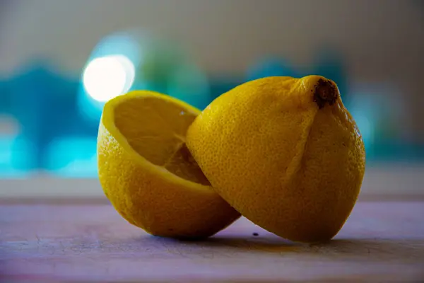 Ev mutfağında limonu ikiye böl. Tahta bir tahtanın üzerinde ikiye bölünmüş taze bir limon. Yemek pişirme imajını kavra.