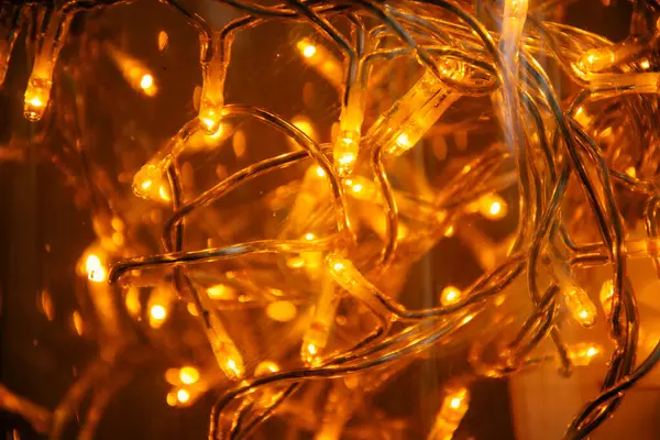 Sıcak sarı ışıklı bir Noel çelengi, yakın çekim, ışığın yumuşak atmosferini gösteriyor. Noel ışıkları fotoğrafı kapatıyor. Noel fotoğrafçılığı arka planlar için idealdir.