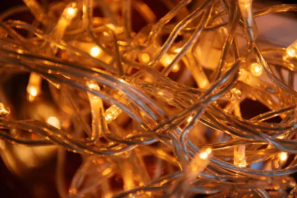 Sıcak sarı ışıklı bir Noel çelengi, yakın çekim, ışığın yumuşak atmosferini gösteriyor. Noel ışıkları fotoğrafı kapatıyor. Noel fotoğrafçılığı arka planlar için idealdir.
