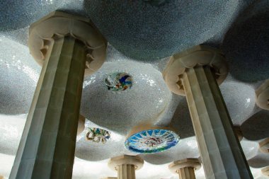 İspanya, Barcelona Park Gell 'deki Hypostyle Salonu' nun mimari detayları. Antoni Gaud 'un tasarladığı renkli mozaik fayanslarla dekore edilmiş tavanı destekleyen devasa taş sütunlar..