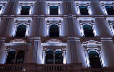 Klasik mimari ve gece vakti bina cepheleri. Klasik İtalyan mimarisinin gece aydınlatmalı Milano cephesi.