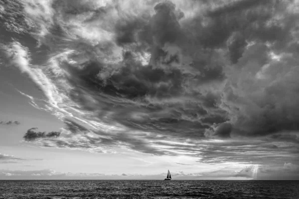 A Storm Is Looming Overhead As A Small Boat Moves Along The Ocean Horizon Black And White