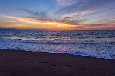 Arka planda İnsanlarla Kum Okyanusunda Günbatımında Ayak İzleri