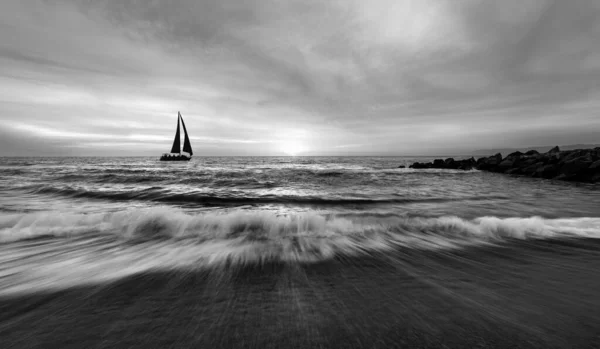A Sailboat Is Sailing Along The Ocean With Birds Flying Overhead And A Wave Breaking On Shore