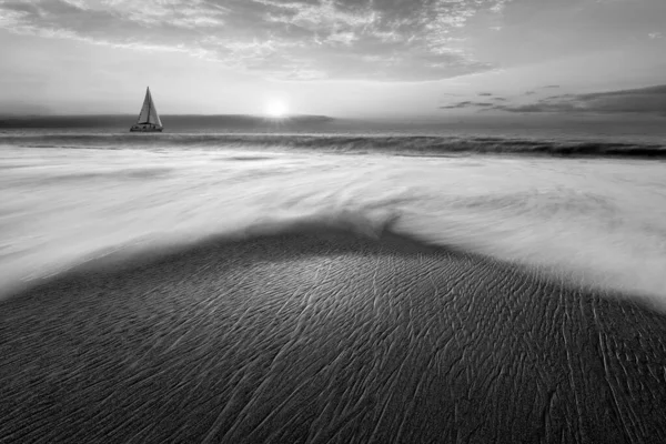 A Sailboat Is Sailing Along The Ocean With A Wave Breaking On Shore Black And White