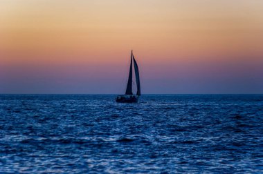 A Sailboat Is Sailing Along The Ocean With A Wave Breaking On Shore