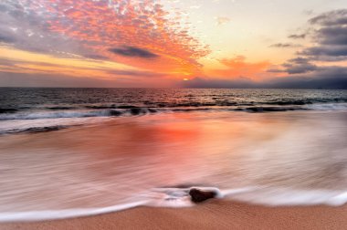 Sahilde dalgalanan güzel bir okyanus gün batımı