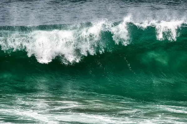 An Big Ocean Wave Is Breaking With White Spray At The Top