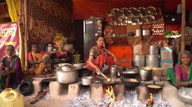 NAGPUR, MAHARASHTRA, INDIA 25 HAZİRAN 2023: İnsanlar, eski mutfağın kırsal kesimlerinde, toprak chulhas 'ta yakacak odun kullanarak taze yemek pişiriyor ve pişiriyor..