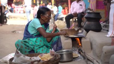 NAGPUR, MAHARASHTRA, INDIA 25 HAZİRAN 2023: İnsanlar, eski mutfağın kırsal kesimlerinde, toprak chulhas 'ta yakacak odun kullanarak taze yemek pişiriyor ve pişiriyor..