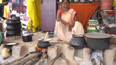 NAGPUR, MAHARASHTRA, INDIA 25 HAZİRAN 2023: İnsanlar, eski mutfağın kırsal kesimlerinde, toprak chulhas 'ta yakacak odun kullanarak taze yemek pişiriyor ve pişiriyor..