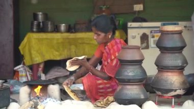 NAGPUR, MAHARASHTRA, INDIA 25 HAZİRAN 2023: İnsanlar, eski mutfağın kırsal kesimlerinde, toprak chulhas 'ta yakacak odun kullanarak taze yemek pişiriyor ve pişiriyor..