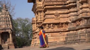 Renkli sarili kadın turist, Hindistan 'daki UNESCO Dünya Mirası Bölgesi, Khajuraho Tapınağı' nda yürüyor..