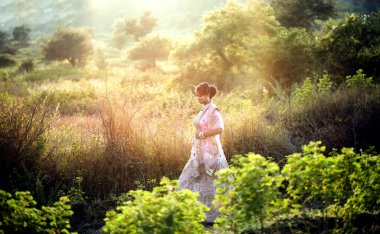 Doğada gün batımında geleneksel kıyafetler giyen güzel bir gelin portresi..