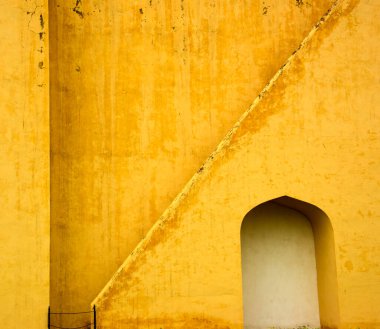 Antik astronomik gözlem evi Jantar Mantar, Jaipur, Rajasthan, Hindistan 'daki klasik sarı duvarlardaki soyut kalıplar.