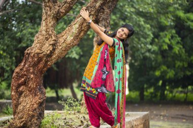 Ağaç gövdesinin yanında genç bir kız ve açık havanın tadını çıkarıyor.